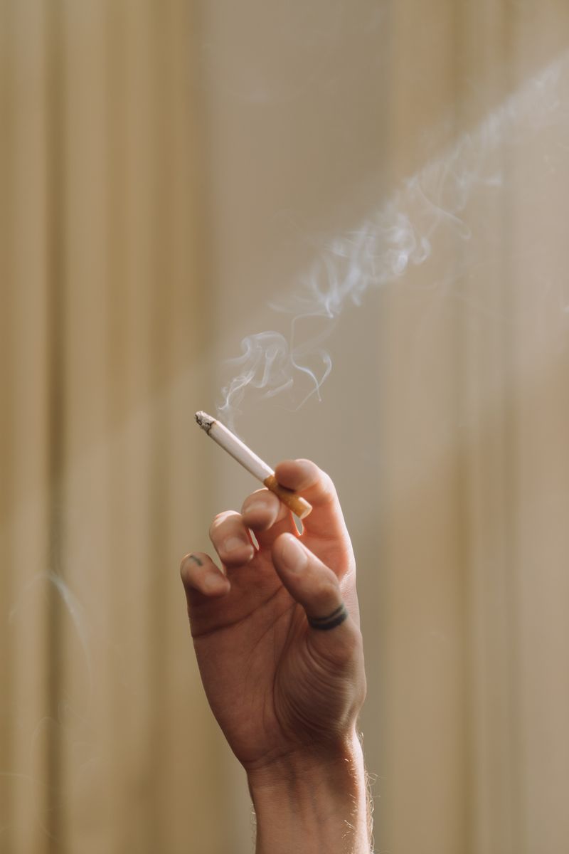 Ruka drziaca zapalenu cigaretu s dymom
